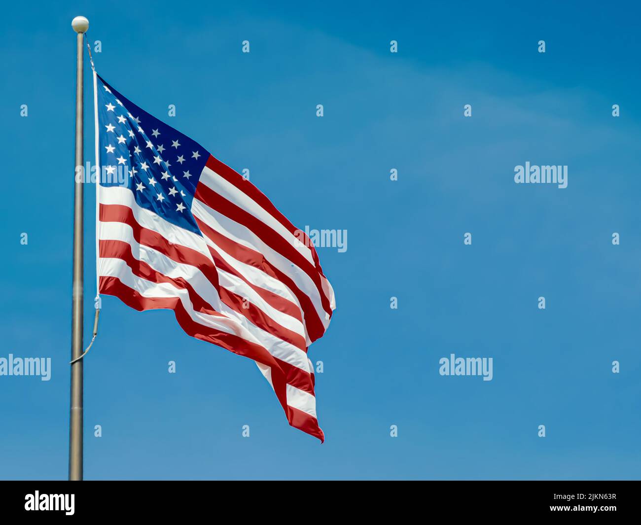 The flag of the United States of America on a flagpole with background ...