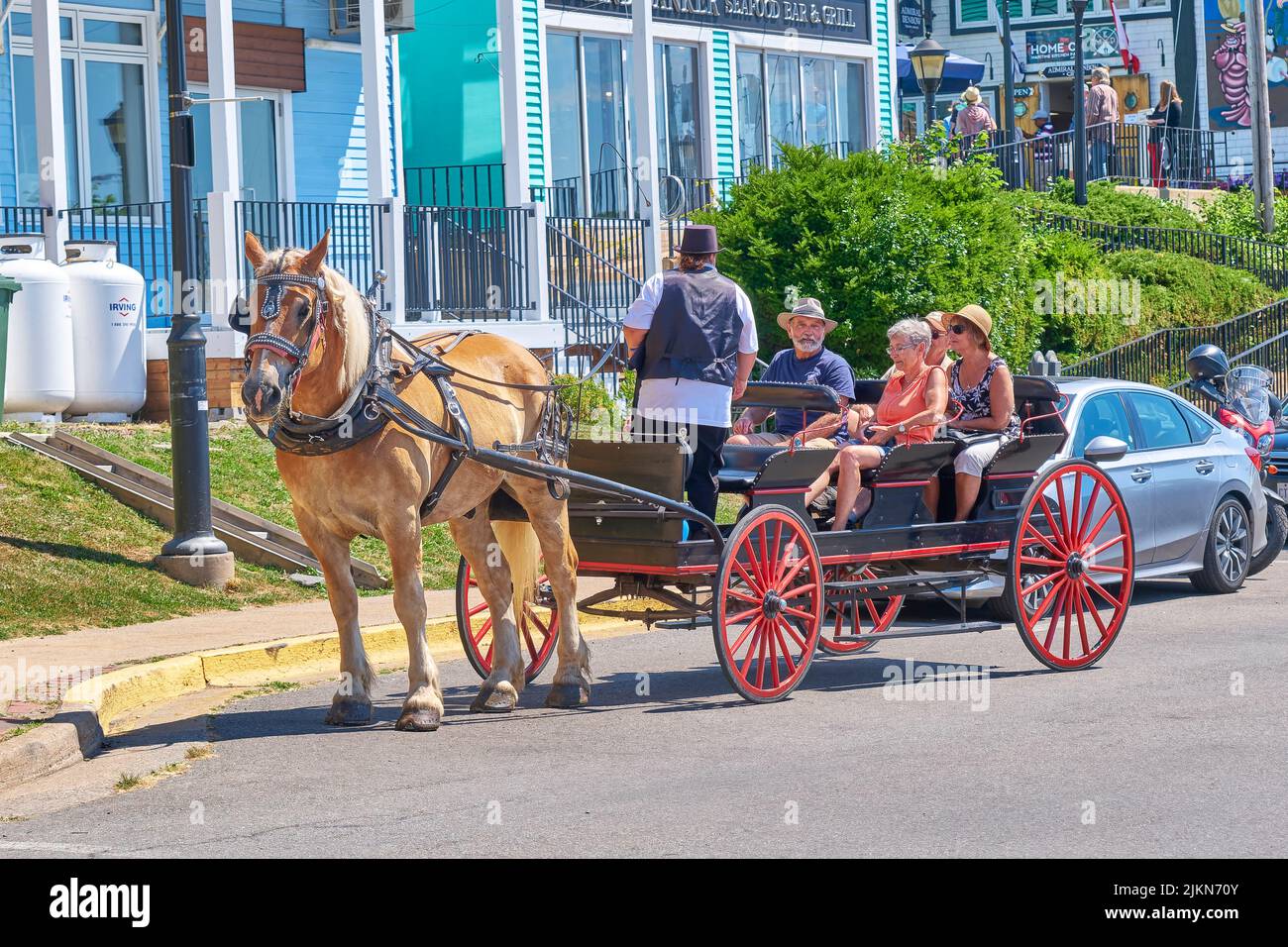 Tourist enjoy a horse drawn carriage tour of historic Lunenburg Nova Scotia. Stock Photo