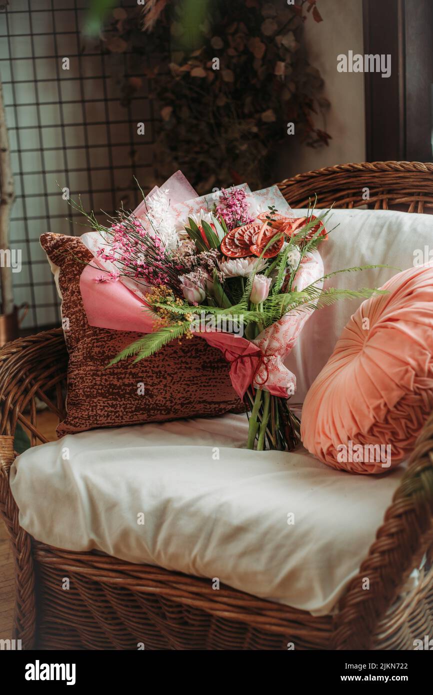 A vertical shot of a tropical pink green bouquet with anthuriums on a bed Stock Photo