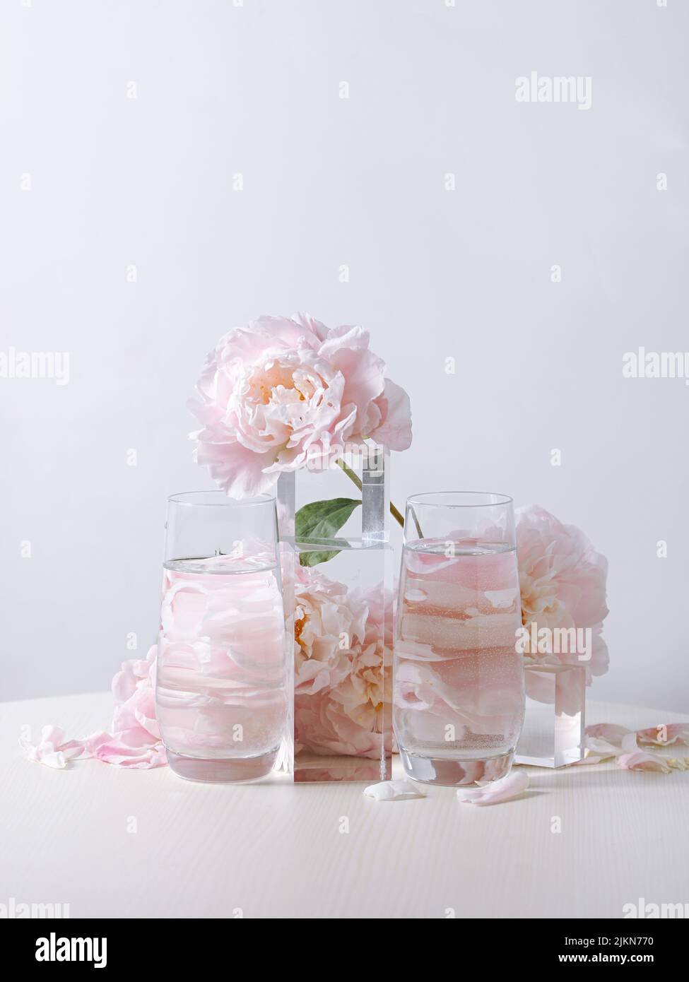 A vertical shot of beautiful pink peony flowers in a glass vase on a ...