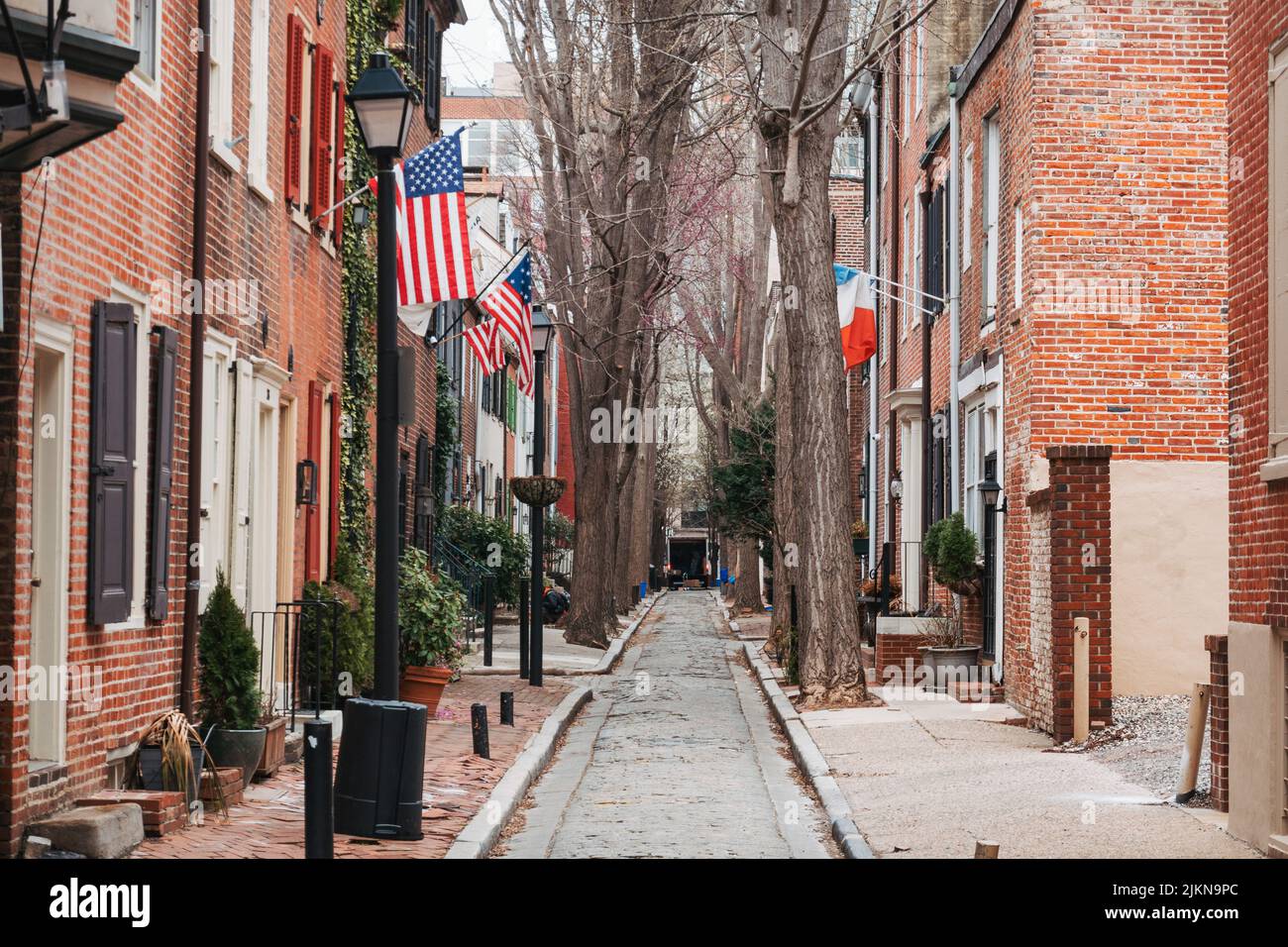 American and French flags from brick row homes in a narrow street in Philadelphia, USA Stock Photo