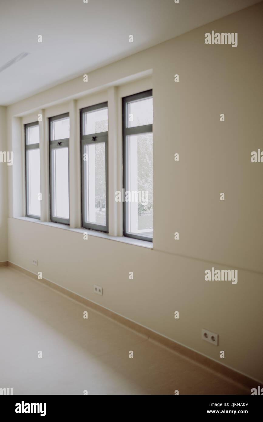 A vertical shot of an empty room with four windows Stock Photo - Alamy