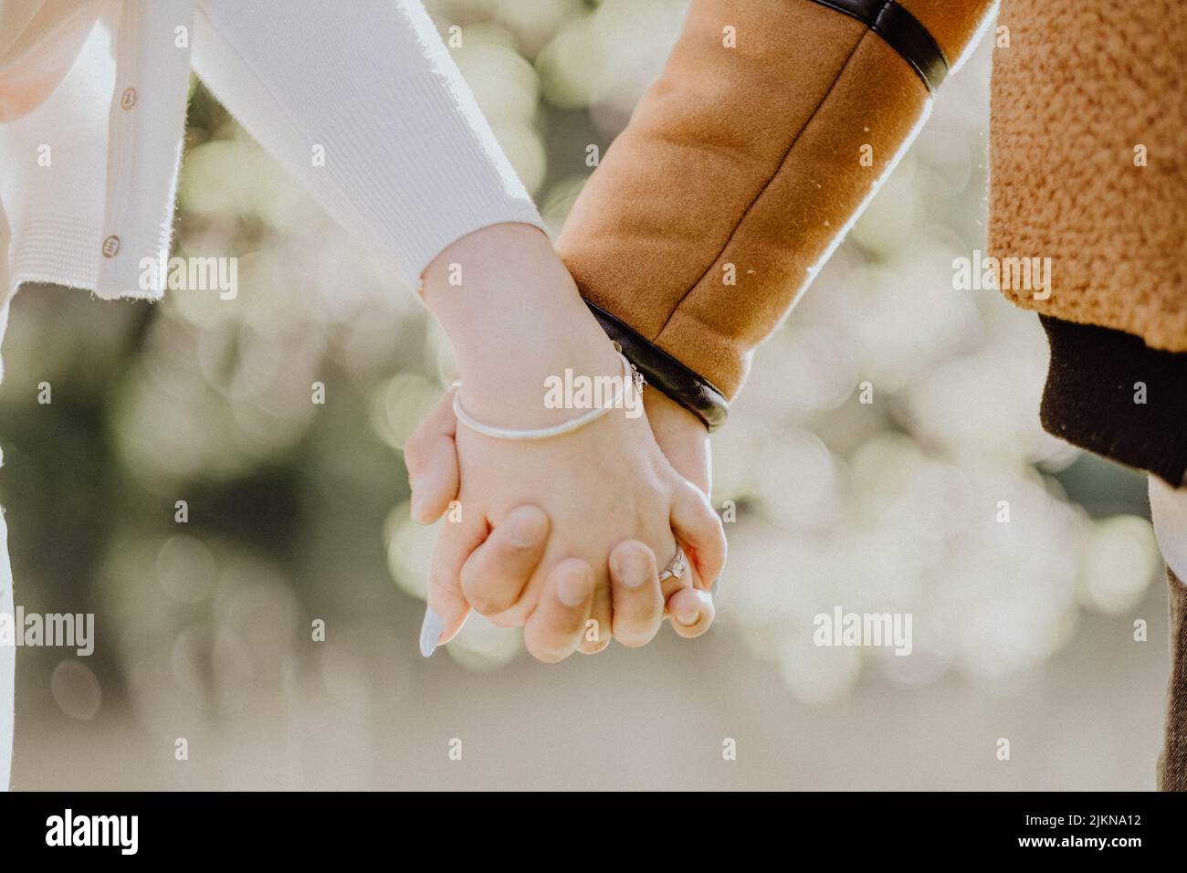 A shallow focus close-up of couple's hands holding Stock Photo
