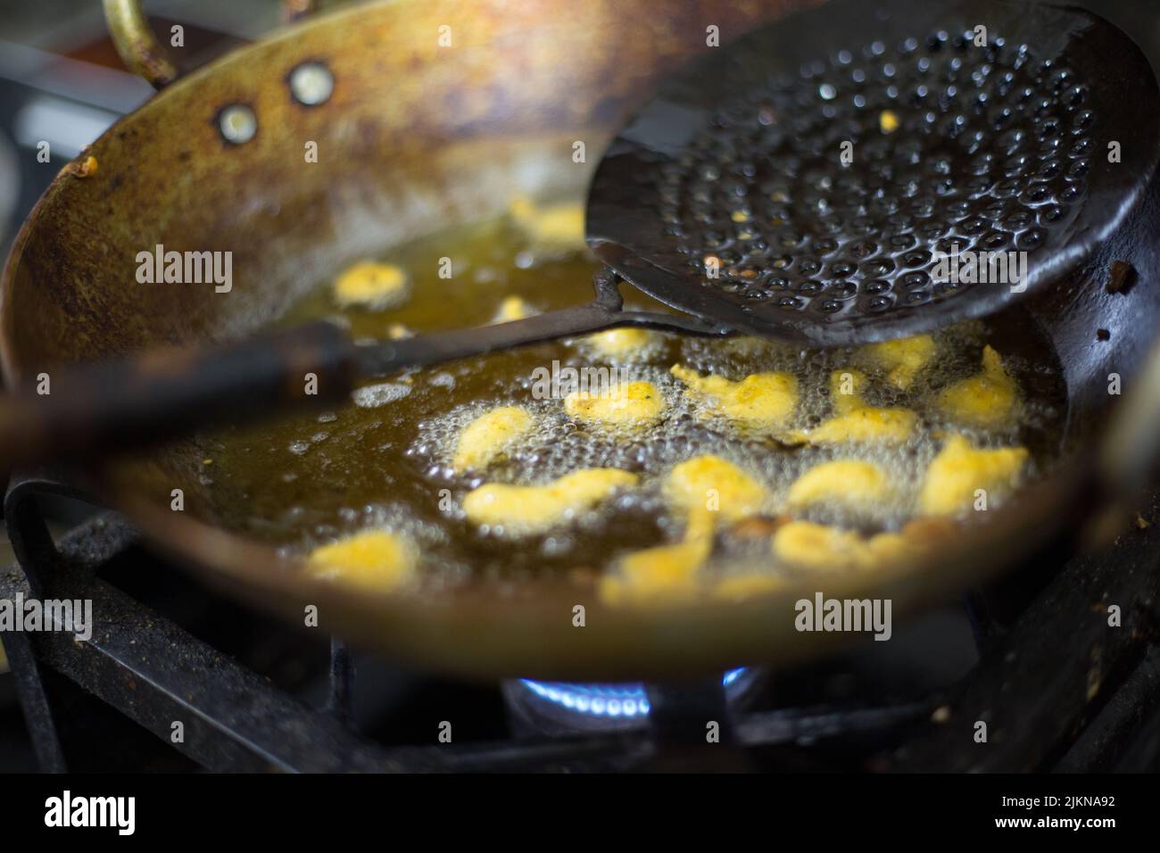 A closeup of a frying pan with oil and ladle in it on a stove Stock