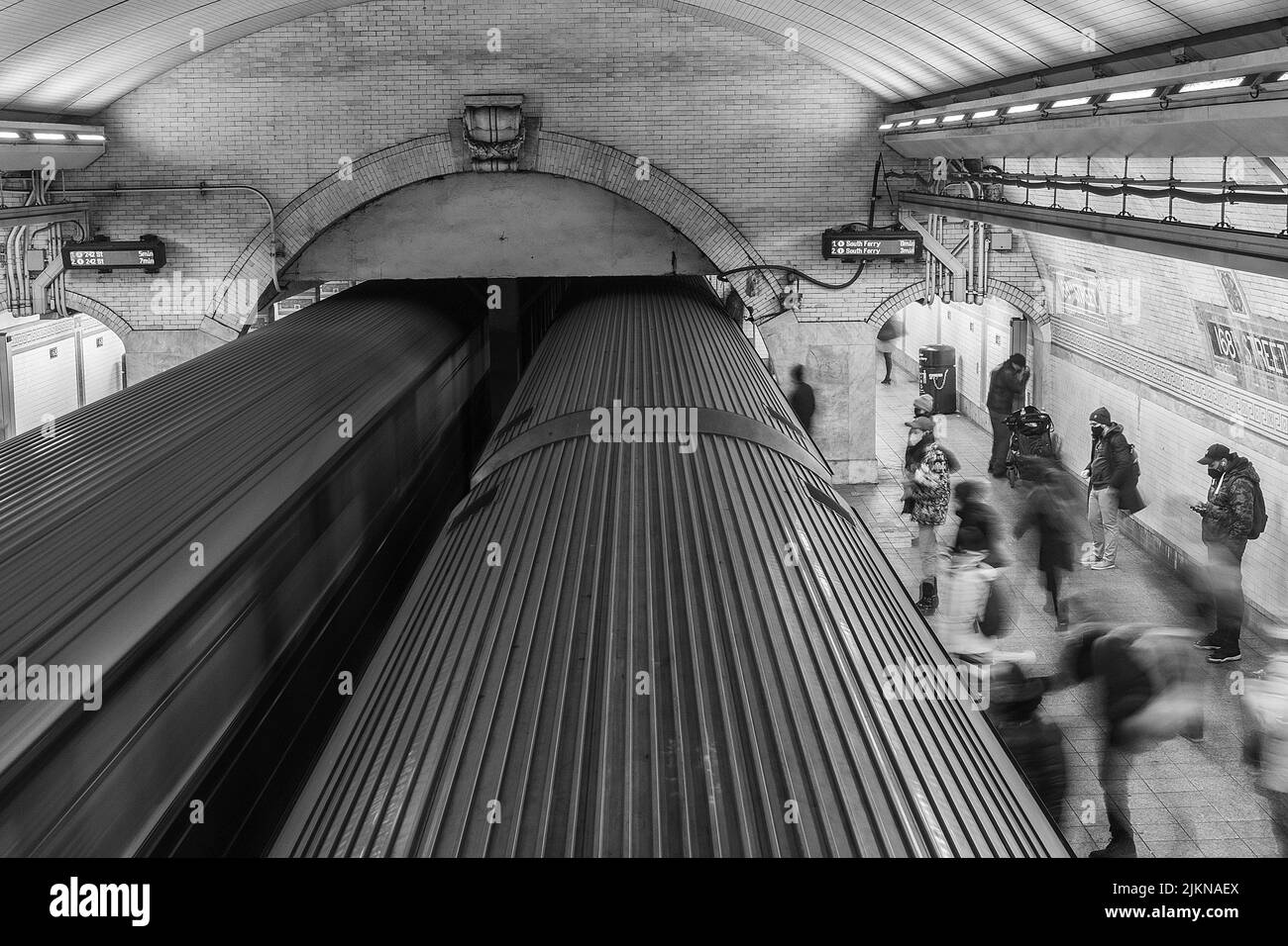 A grayscale long exposure shot of people rushing to a train at a ...