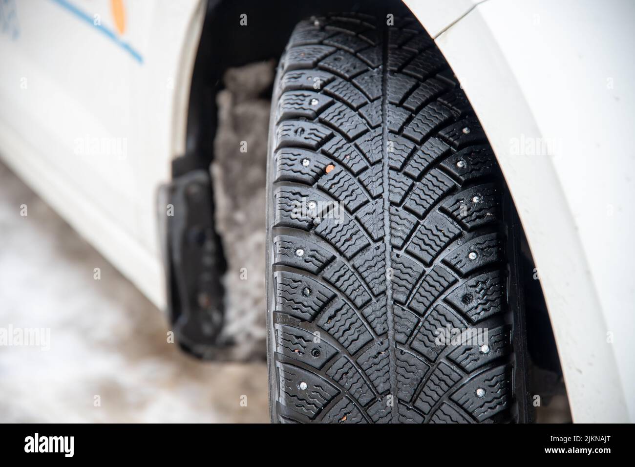 A closeup of a winter tire on a white car Stock Photo