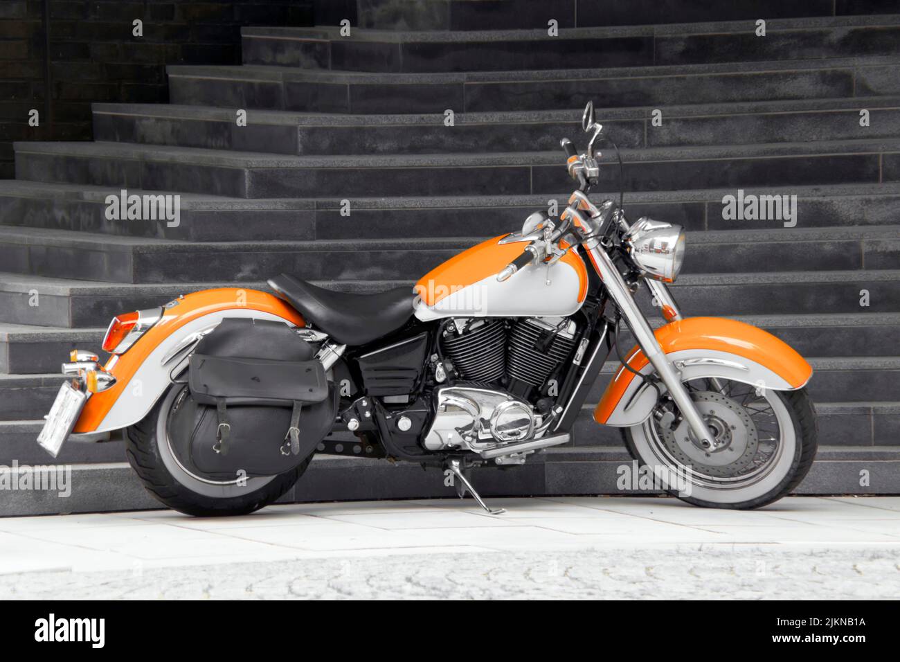 A modern orange motorcycle parked outdoors Stock Photo