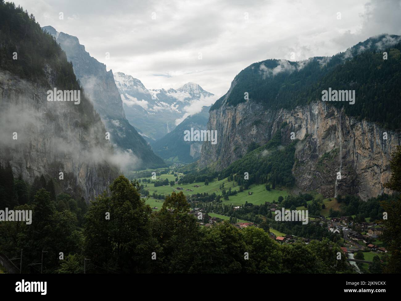 The cloudy blue sky over the rocky landscapes and green field in spring Stock Photo