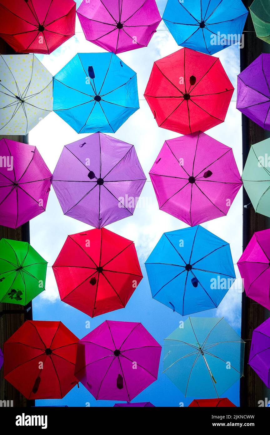 Protection from the sun under a rainbow coloured beach umbrella backlit  from the afternoon sun Stock Photo - Alamy