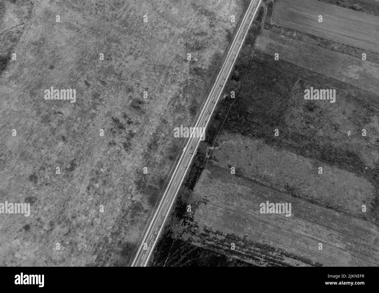 an aerial view of a straight road on a field in black and white Stock ...