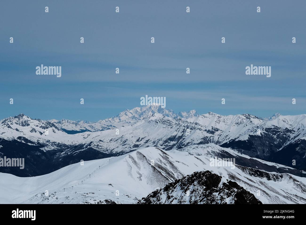 An aerial view of beautiful mountains covered in snow under a blue sky ...