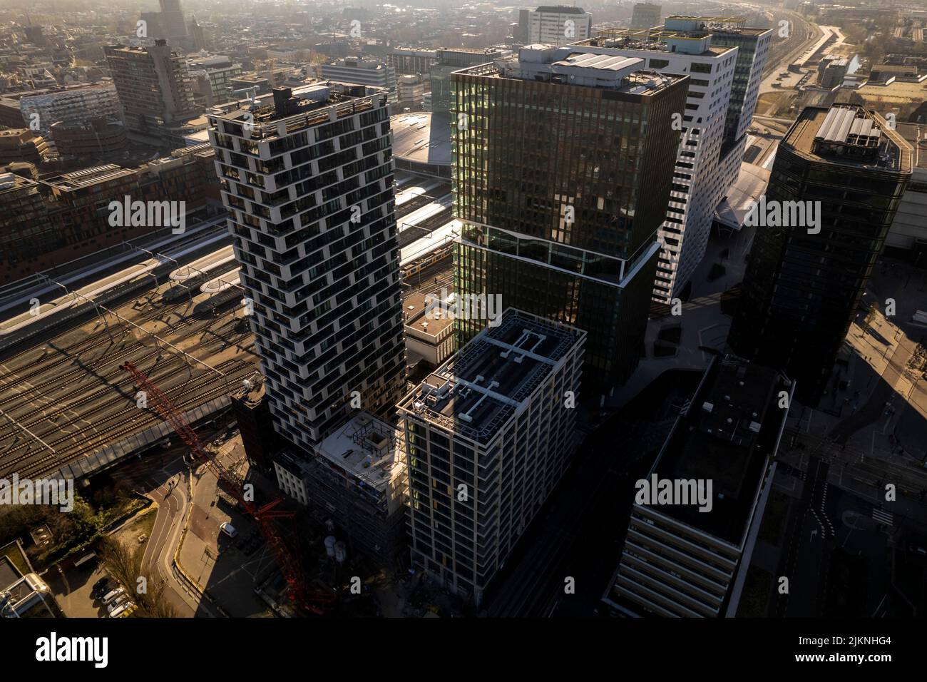 Aerial view of high rise office real estate buildings at infrastructure central train station of Utrecht in early morning sun backlight. Stock Photo