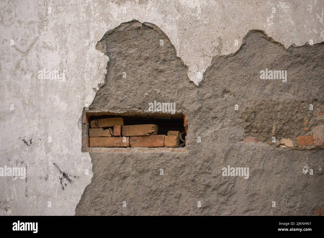 A damaged concrete wall with bricks in the hole Stock Photo Alamy