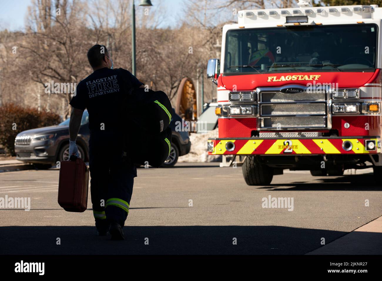 Flagstaff, Arizona, USA - January 7, 2022: A firefighter walks back to their firetruck with their paramedic supplies. Stock Photo