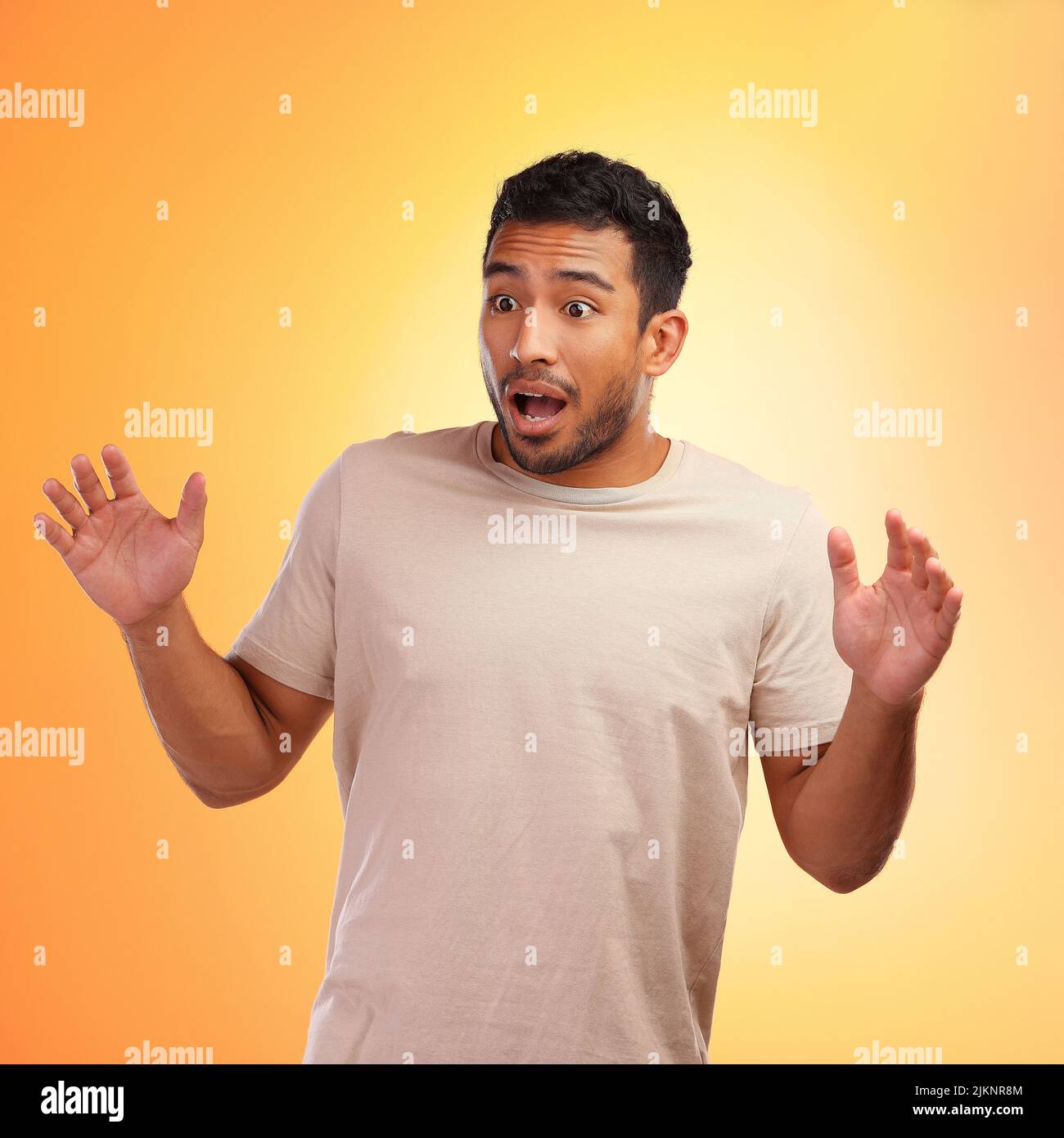 What just happened. a young man looking surprised while standing against a yellow background. Stock Photo