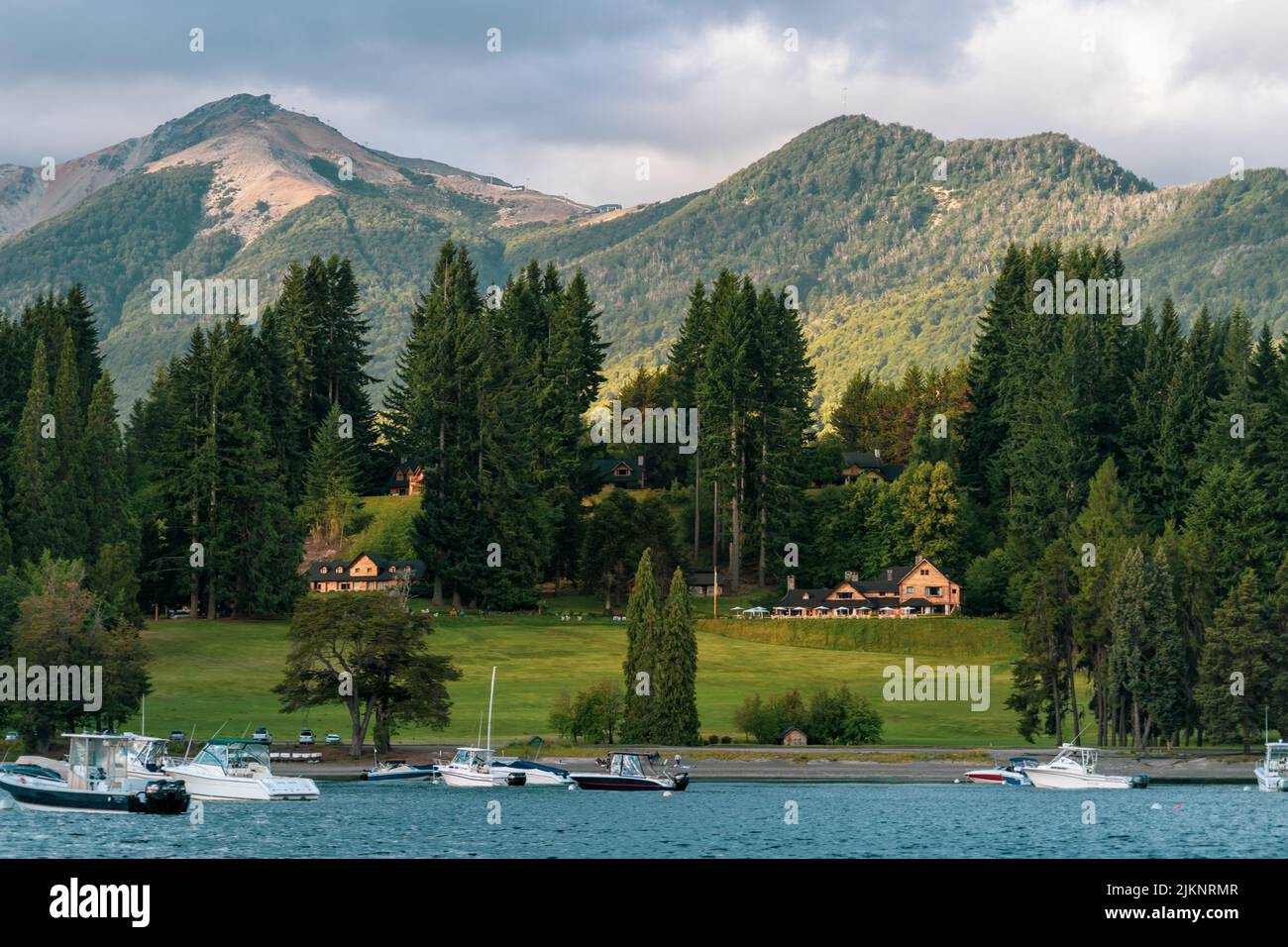 A beautiful view of Cumelen Country Club on a sunny day with mountains and cloudy sky in the background in Villa La Angostura, Neuquen, Argentina Stock Photo