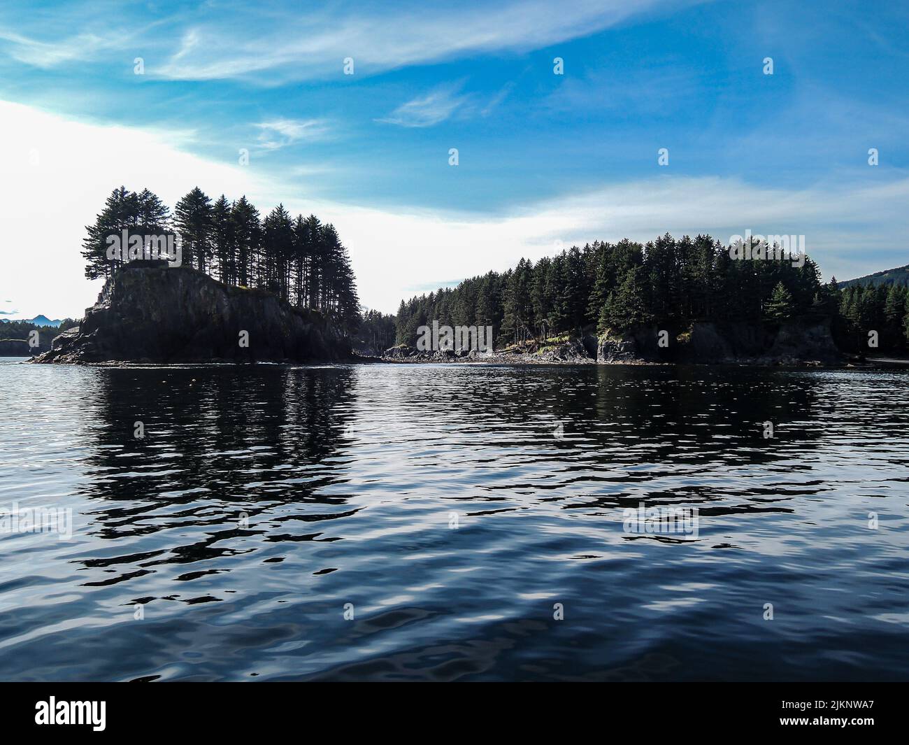 The wavy water with the reflection of dense trees of Kodiak island in