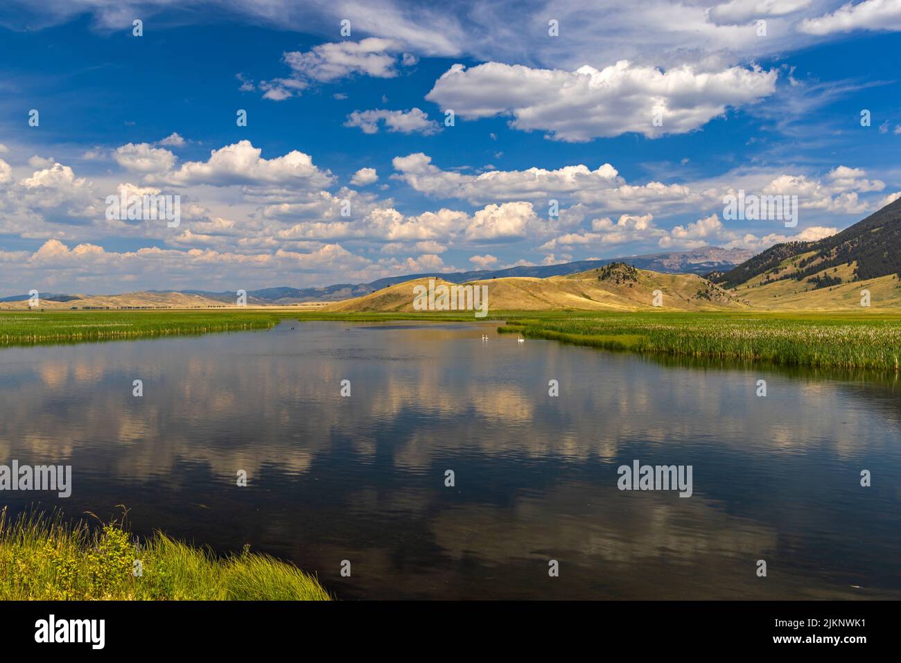 The clouds reflect on the water of Flat Creek at the National Elk Refuge in the Jackson Hole area of the state of Wyoming, USA.. Stock Photo