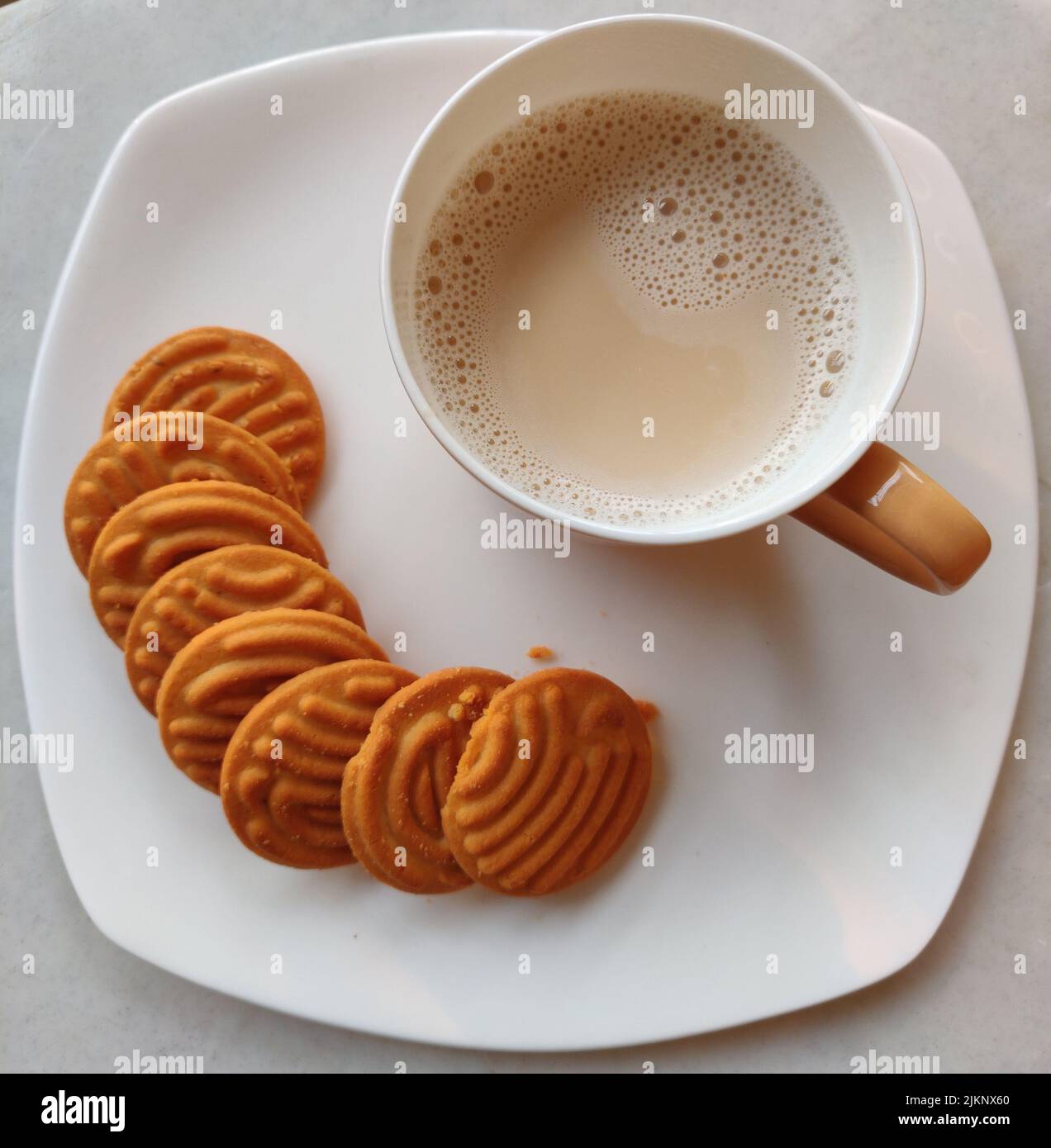 A top view of a cup of milk tea and cookies on a white plate Stock Photo -  Alamy