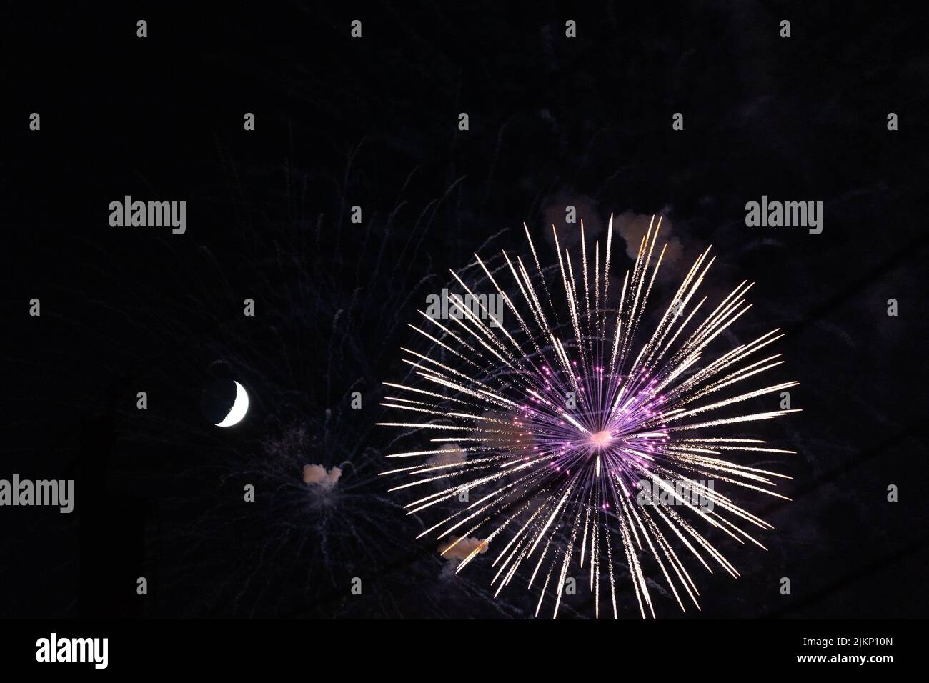 The bright fireworks in the night sky with half moon Stock Photo Alamy