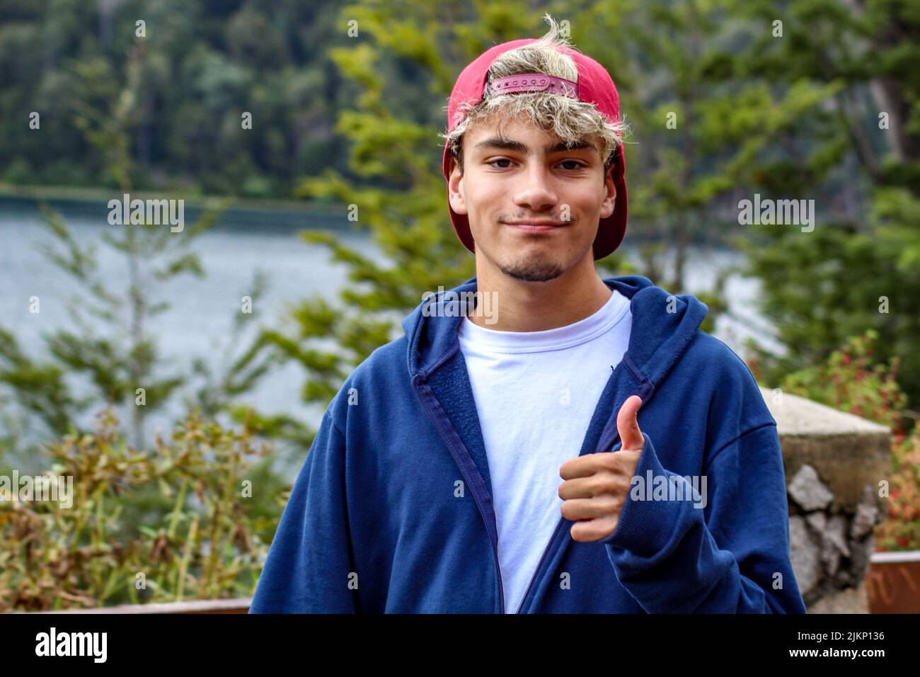 A selective focus shot of a Caucasian man with his hat backwards  showing the thumb up in the park Stock Photo