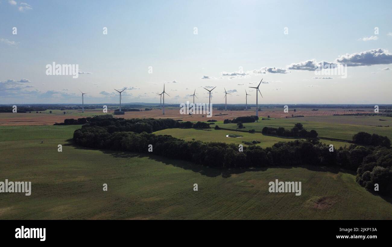 A scenic shot of wind turbines in the green grass meadow under the ...