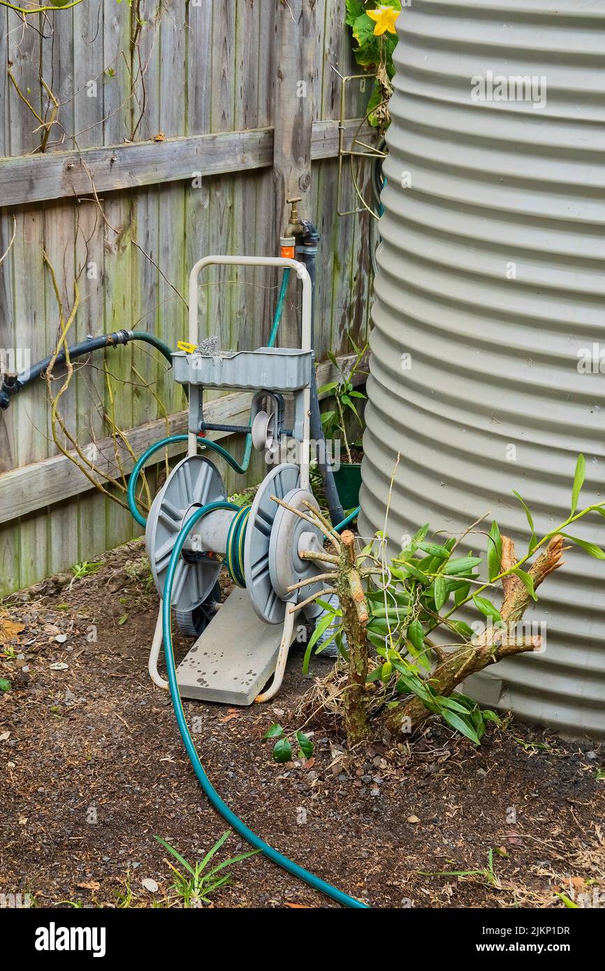 Wind up hose reel beside a rain water tank in a back yard garden