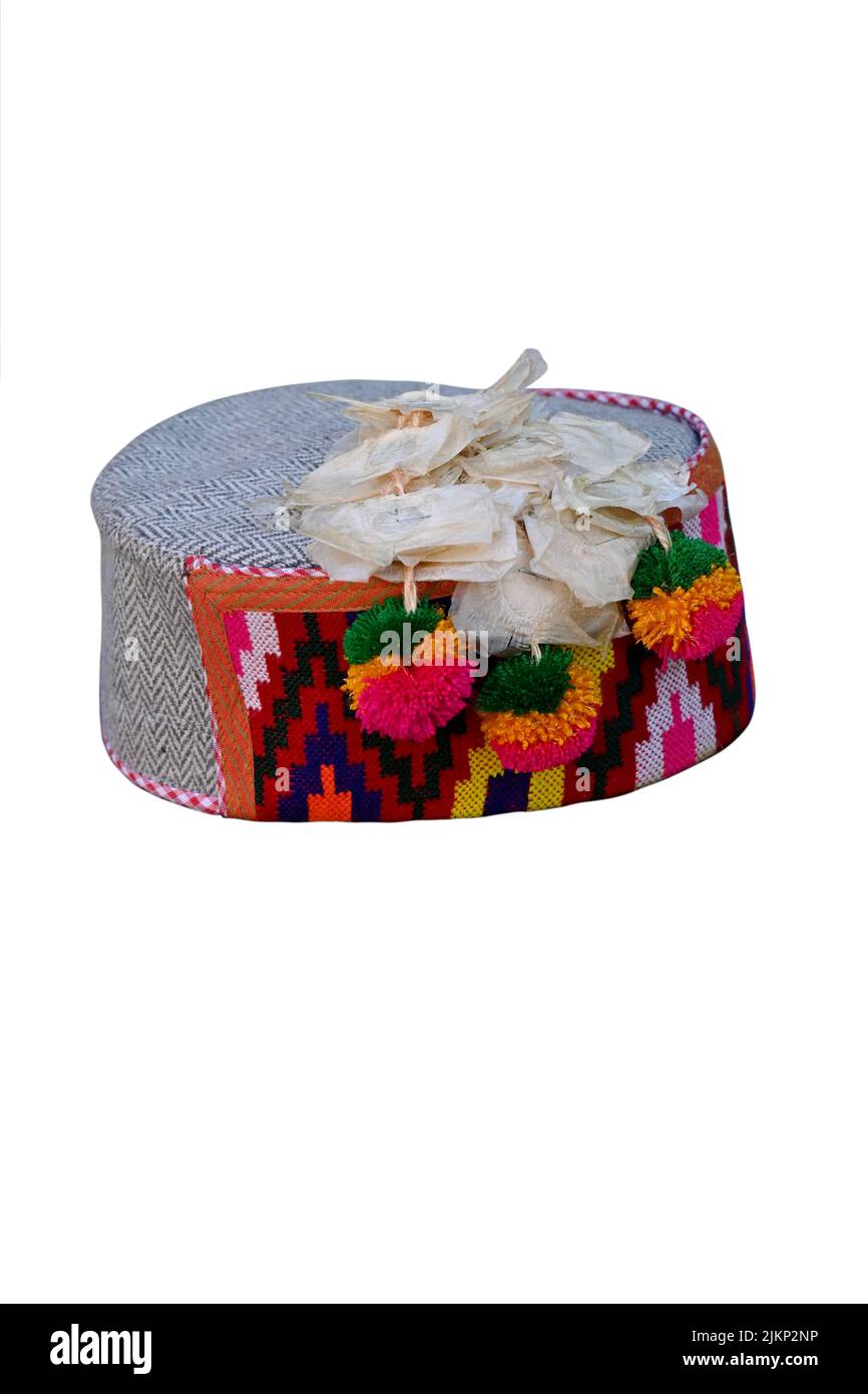 closeup the colorful hand made himachali indian traditional cap with hanging white flowers isolated on white background. Stock Photo