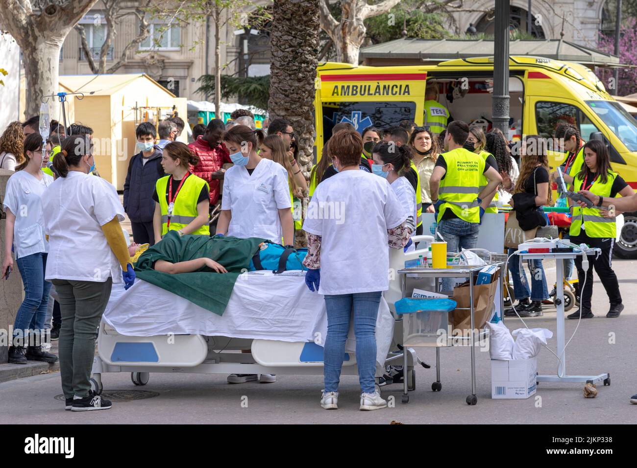 An ambulance car with the staff and a patient lying on the stretcher with people gathered around Stock Photo