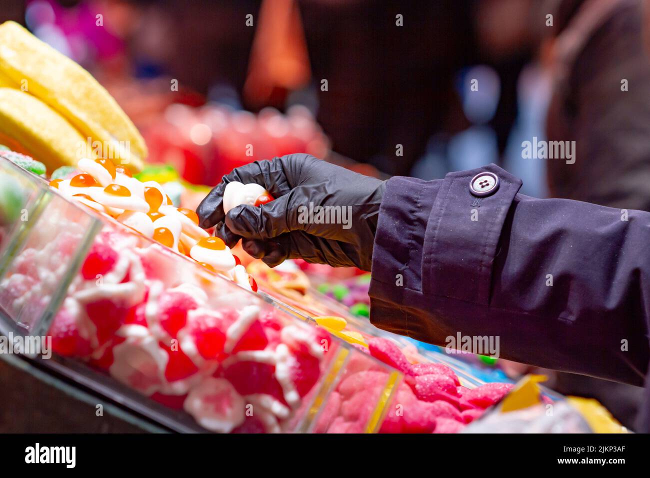 Candy store, unrecognizable hand picking up sweets in a market in