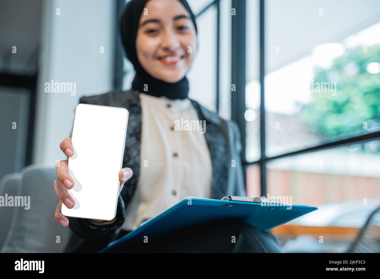 Muslim Woman Showing Blank Mobile Phone Screen To Camera Stock Photo