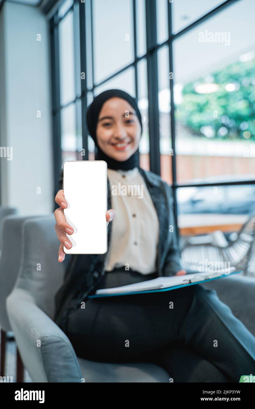 Muslim Woman Showing Blank Mobile Phone Screen To Camera Stock Photo