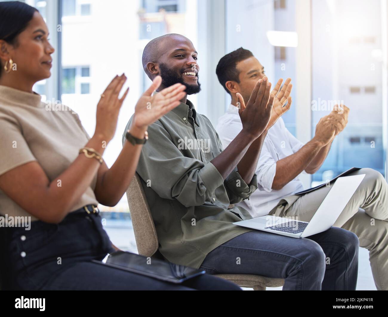 Weve learned alot today. a group of people clapping and smiling during a meeting at work. Stock Photo