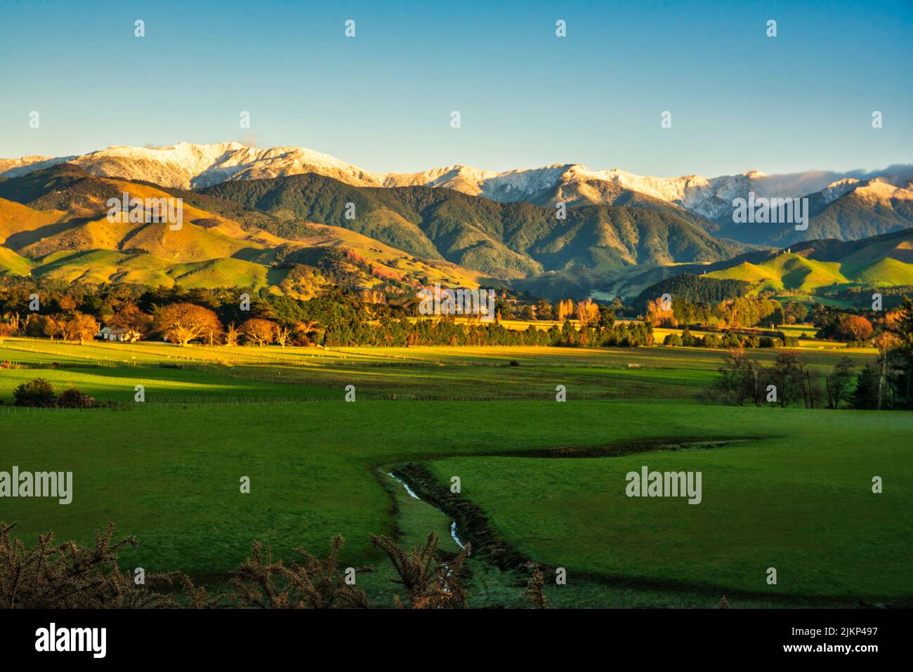 Early morning sun warming the snow capped Tararua mountain range  after some overnight snow on the peaks Stock Photo