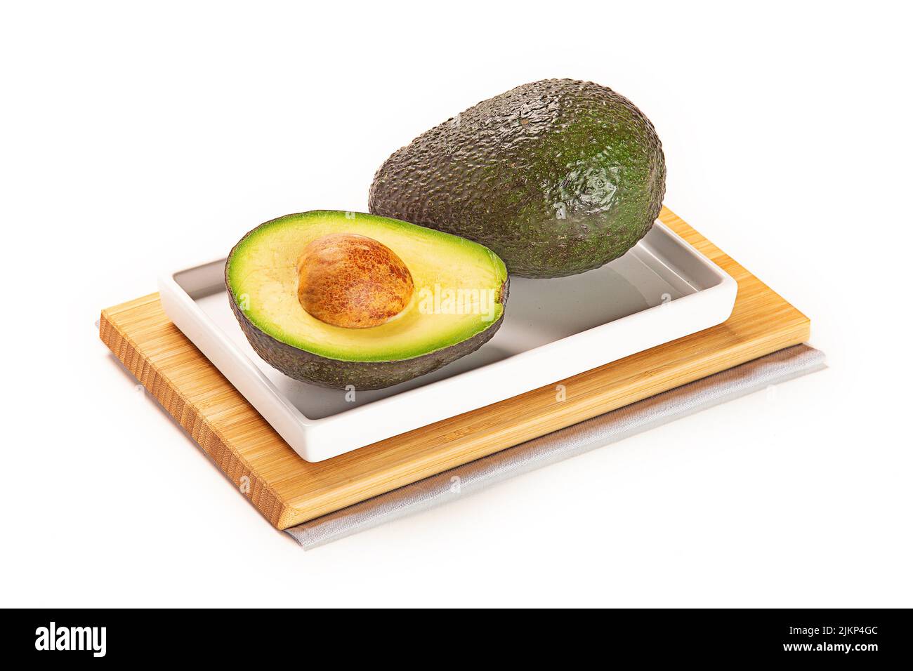 A whole and a sliced avocado on a wooden board isolated on a white ...