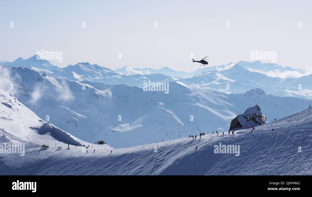 A helicopter flying over snowy skiing mountains Stock Photo - Alamy