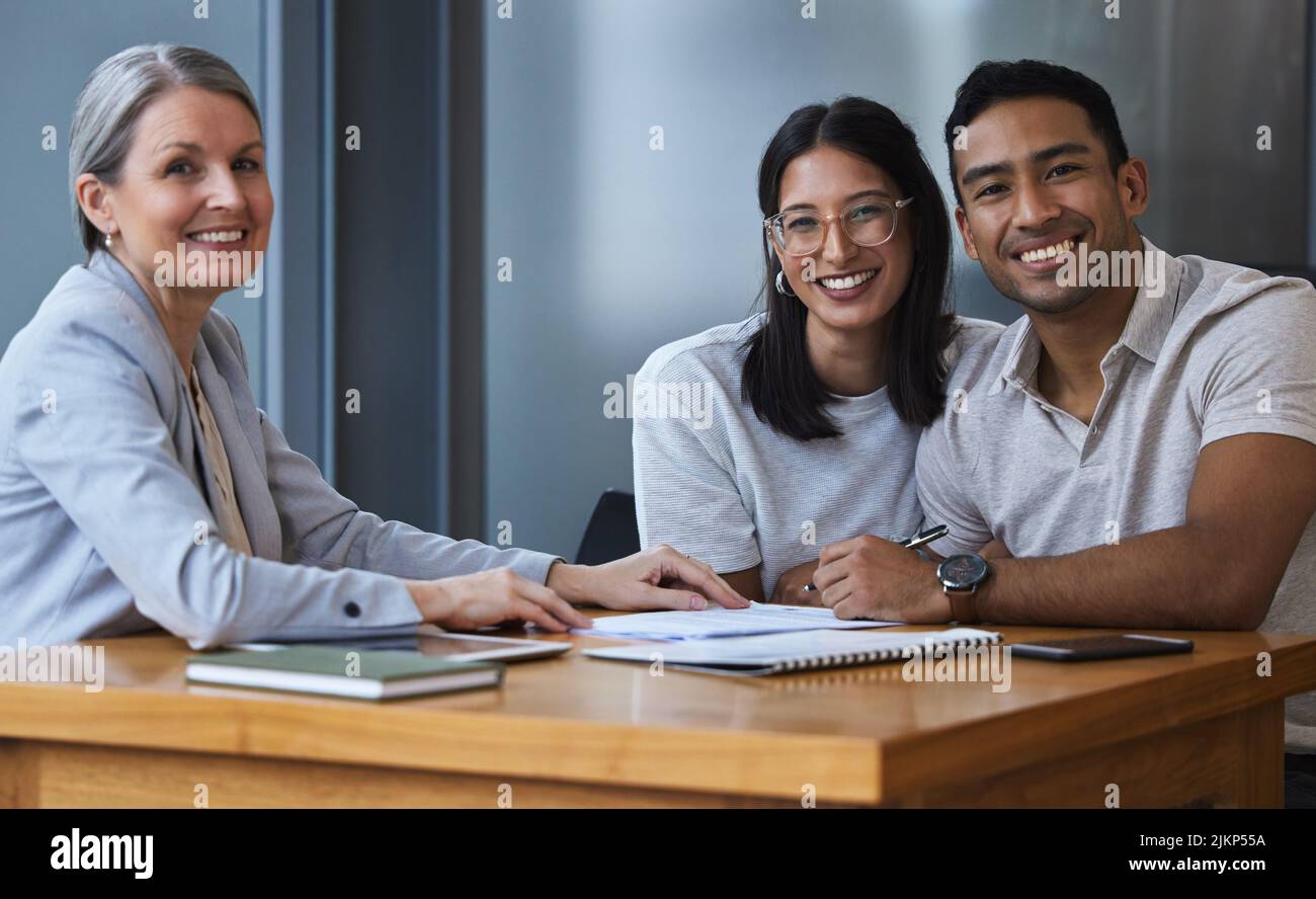 Promise in a pair of calloused hands. Portrait of a young couple meeting with a consultant to discuss paperwork an office. Stock Photo