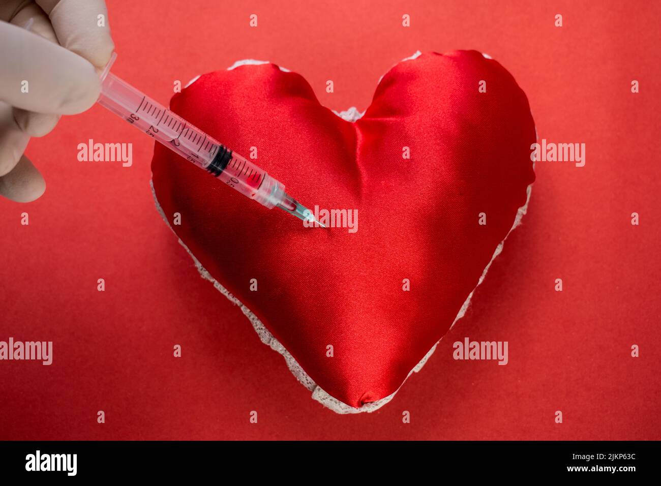 Big heart on a blue background. A smiley face is laid on it with pills. At  the top of the ampoule for injection, next to the scattered tablets and  syringe. Stock Photo