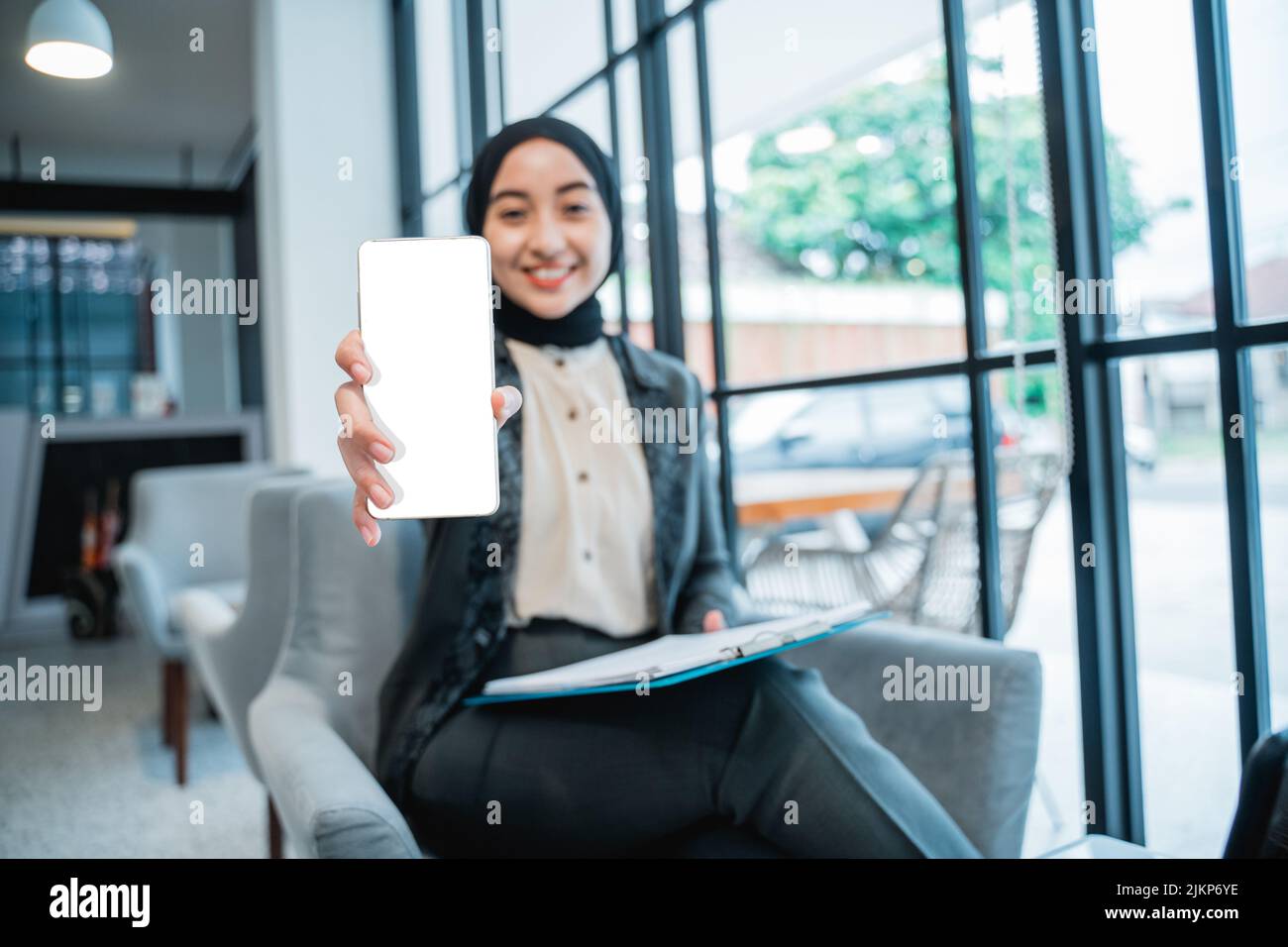 Muslim Woman Showing Blank Mobile Phone Screen To Camera Stock Photo