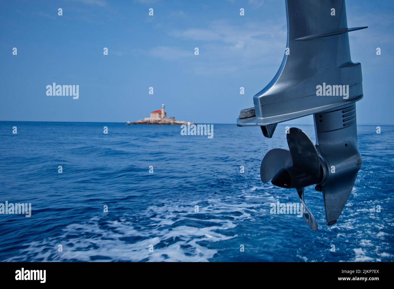 Sailing boat propeller against blue sea with lighthouse in background Stock Photo