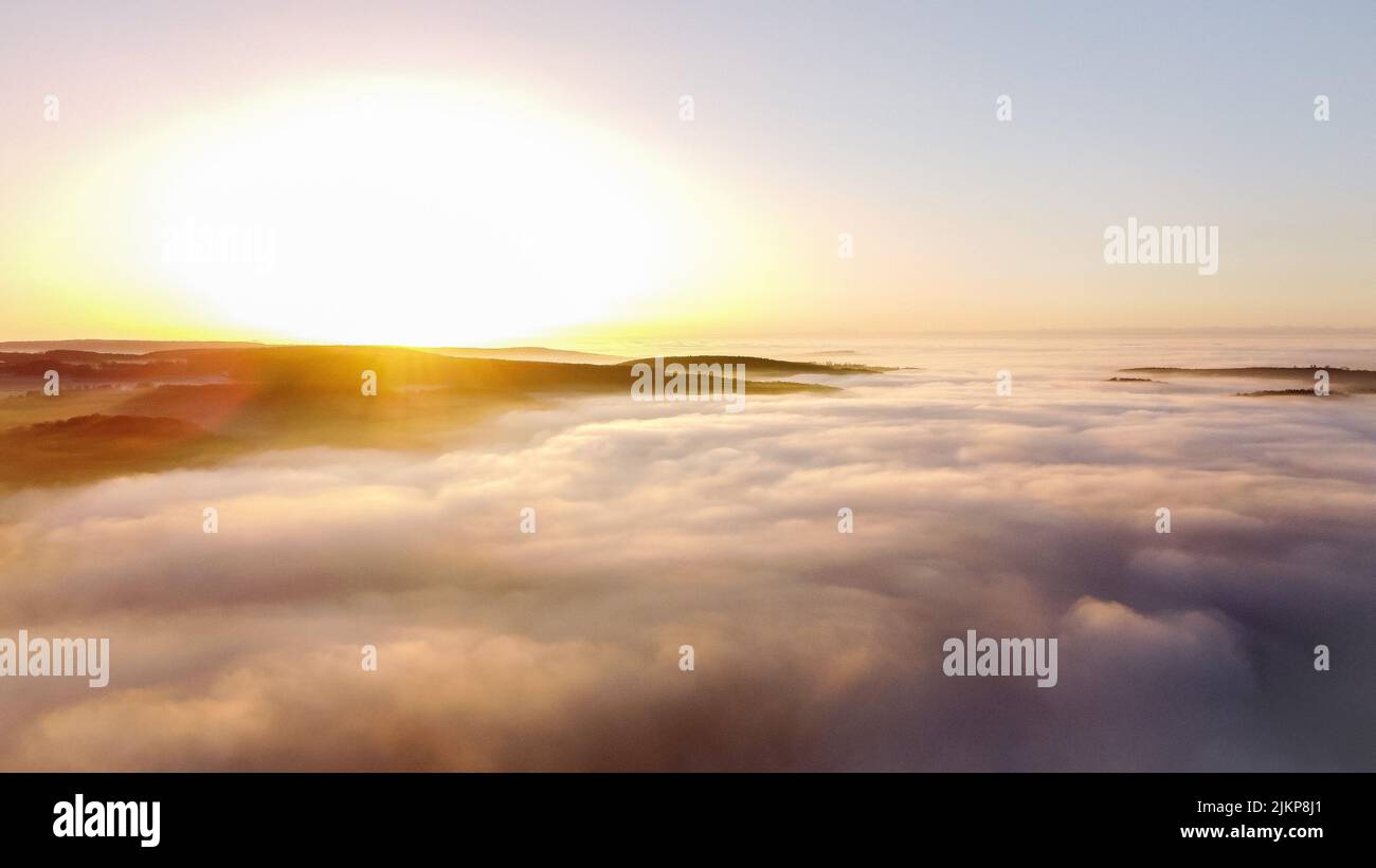 An aerial view of big basin of green leaved trees and plants covered with fog at an epic sunrise Stock Photo