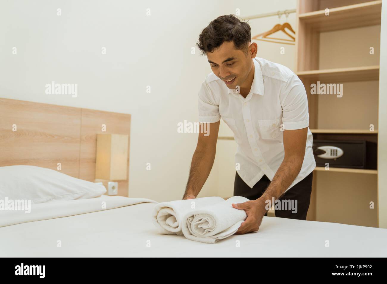 Young asian cleaning boy putting towel on hotel room bed Stock Photo