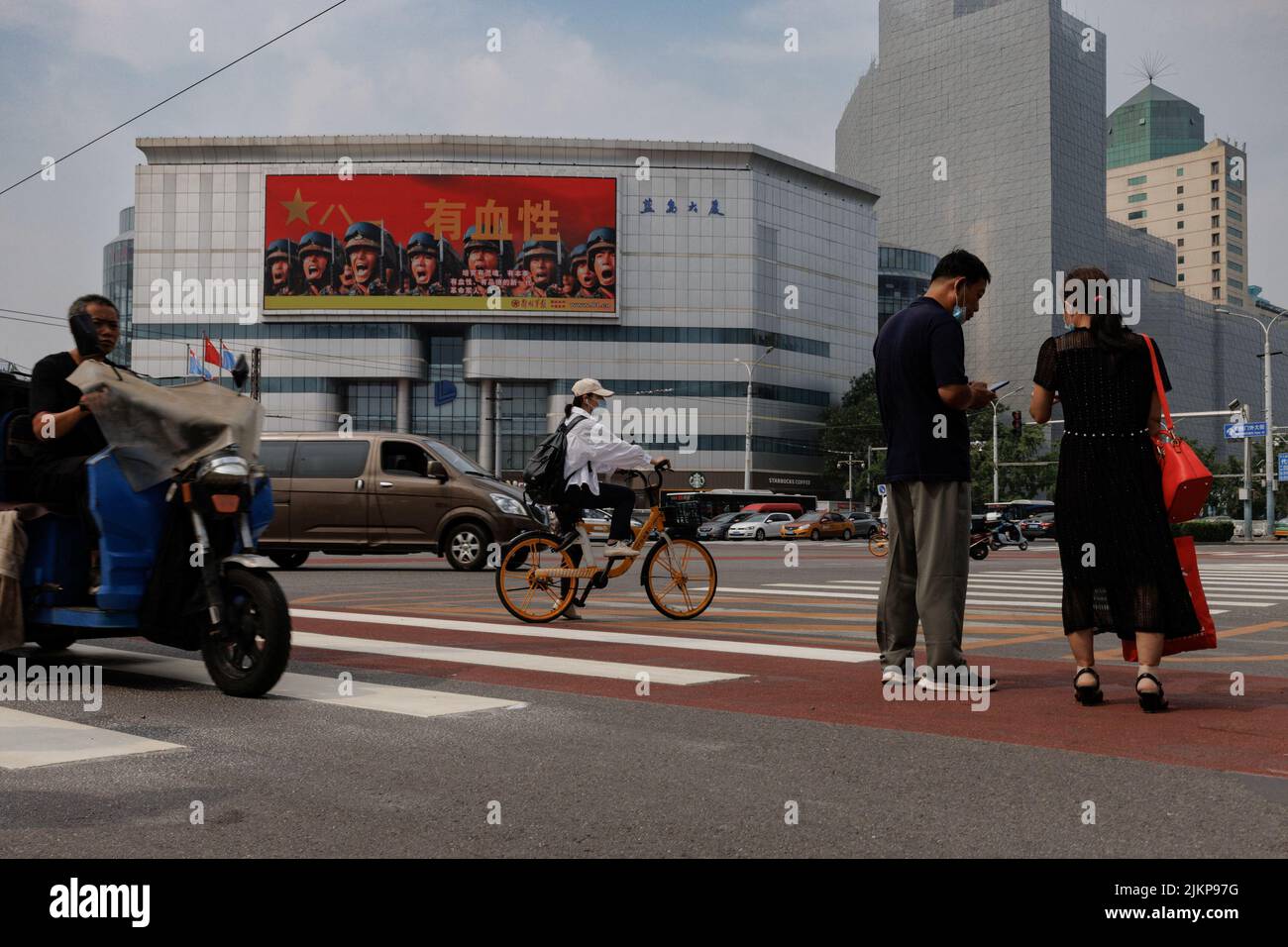 People wait at a traffic light near an image of Chinese People's Liberation Army (PLA) soldiers in Beijing, China, August 3, 2022.   REUTERS/Thomas Peter Stock Photo