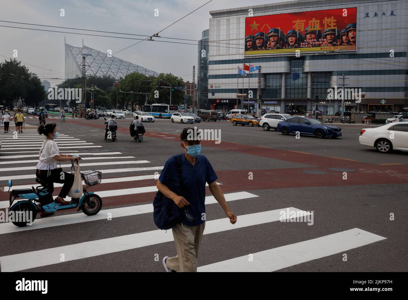 People cross a junction near an image of Chinese People's Liberation Army (PLA) soldiers in Beijing, China, August 3, 2022.   REUTERS/Thomas Peter Stock Photo