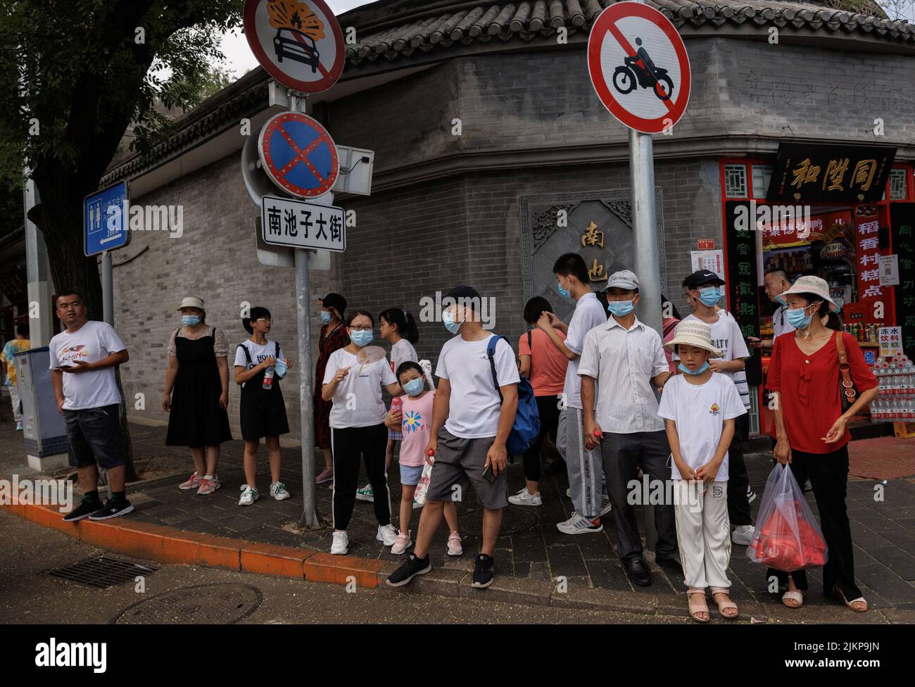 People wear face masks as they stand in a street following a coronavirus disease (COVID-19) outbreak, in Beijing, China, August 3, 2022. REUTERS/Thomas Peter Stock Photo
