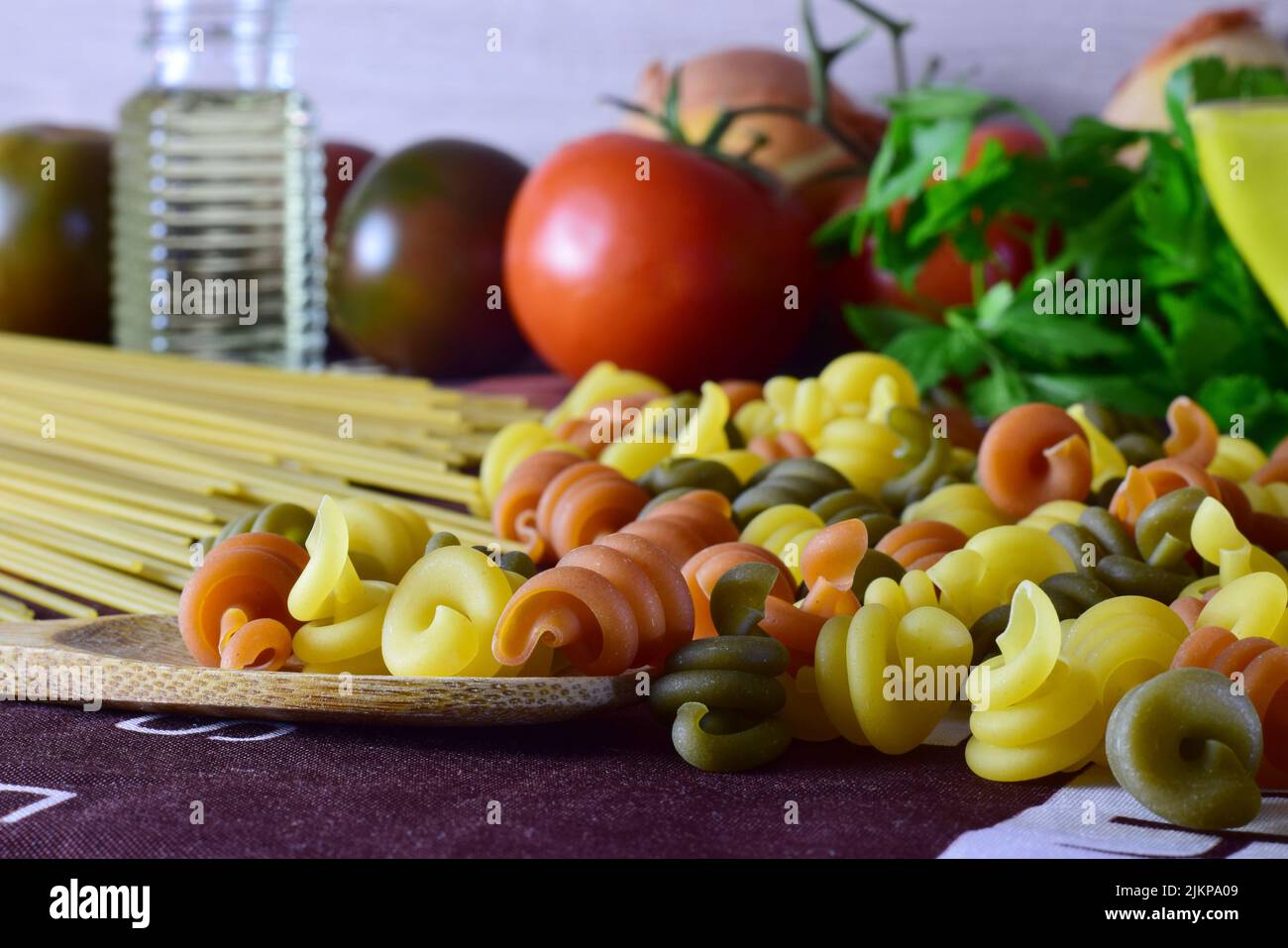 A closeup of colored pasta, and tomatoes with other ingredients. Healthy food. Stock Photo