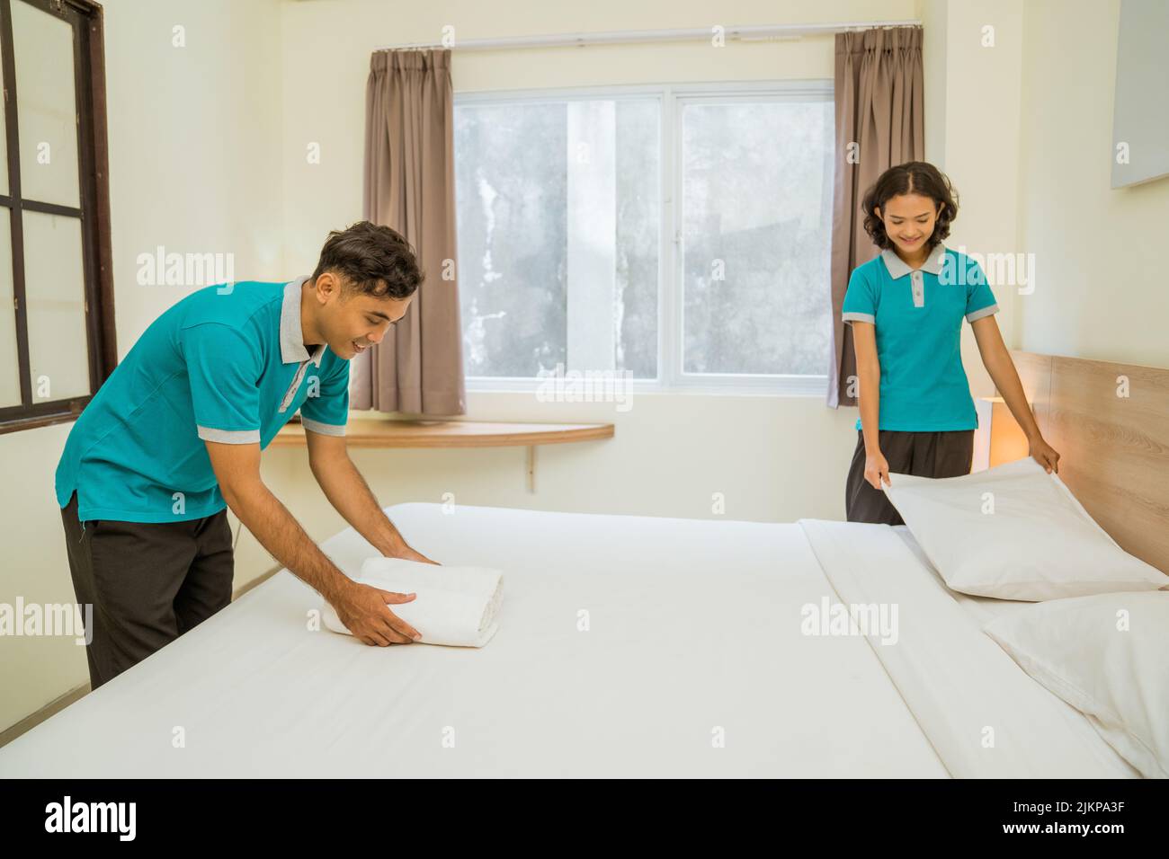 male and female cleaners wearing uniforms making beds Stock Photo Alamy