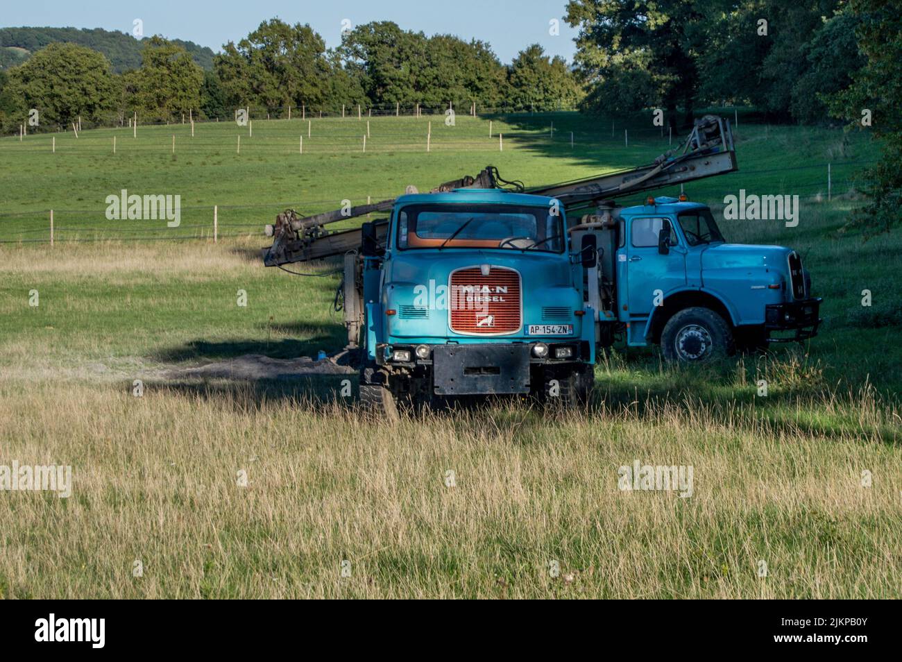 Two old blue trucks with crane abandoned in the field Stock Photo