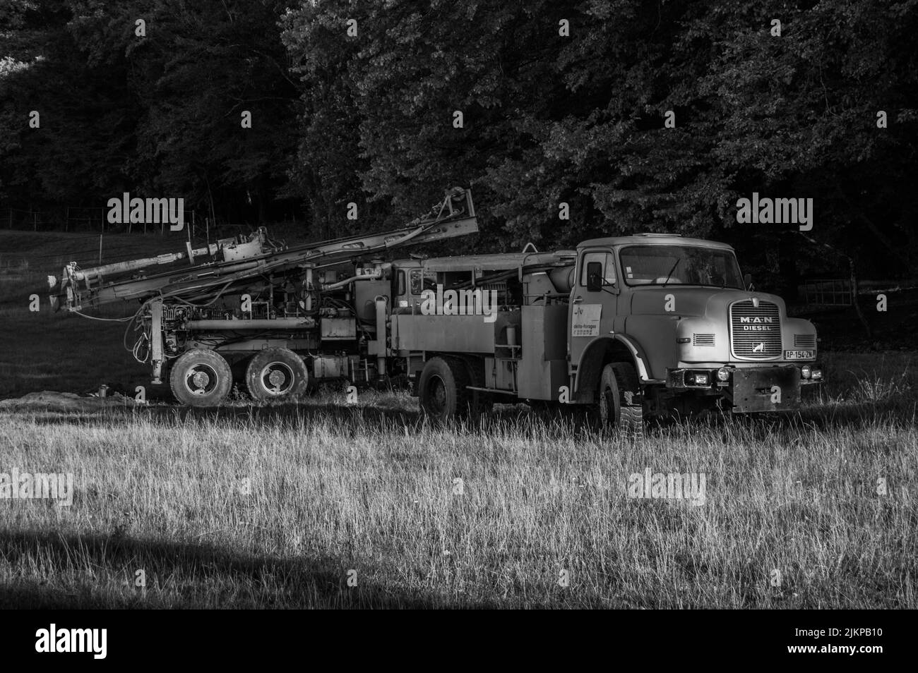 Two old blue trucks with crane abandoned in the field Stock Photo