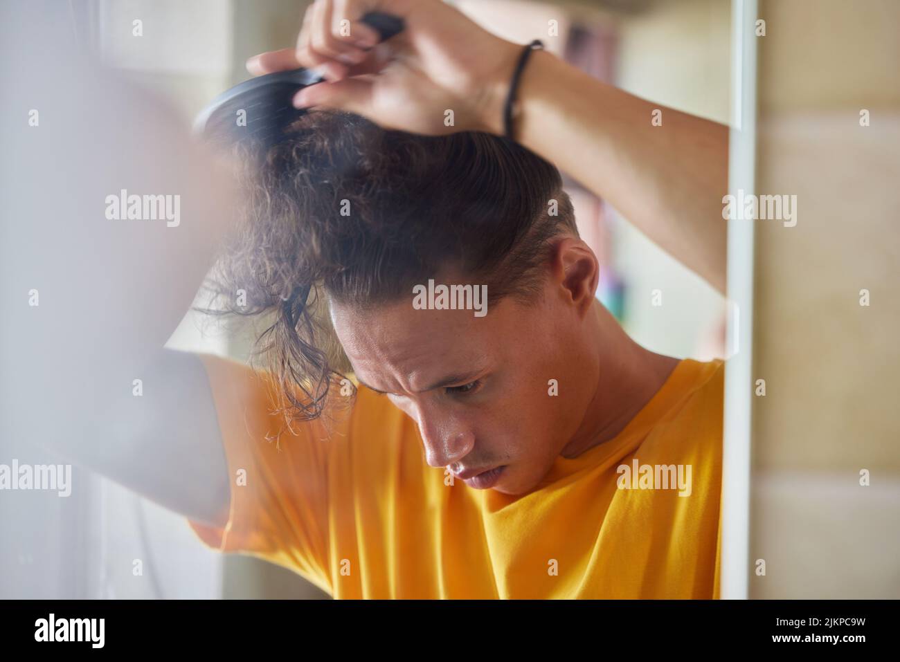 My hair gets so tangled if I dont brush it. a young man brushing his